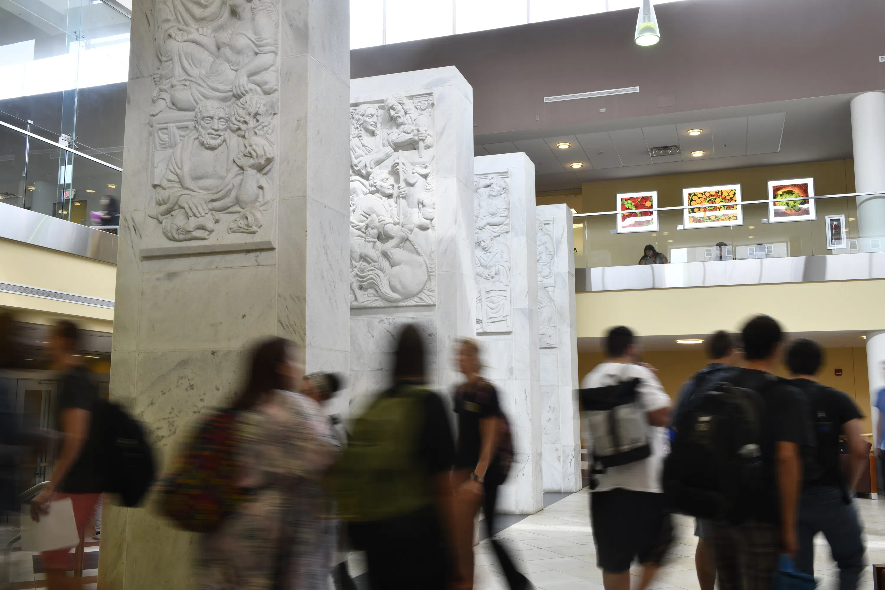 Students walk past four white carved structures known as the Pylons. 