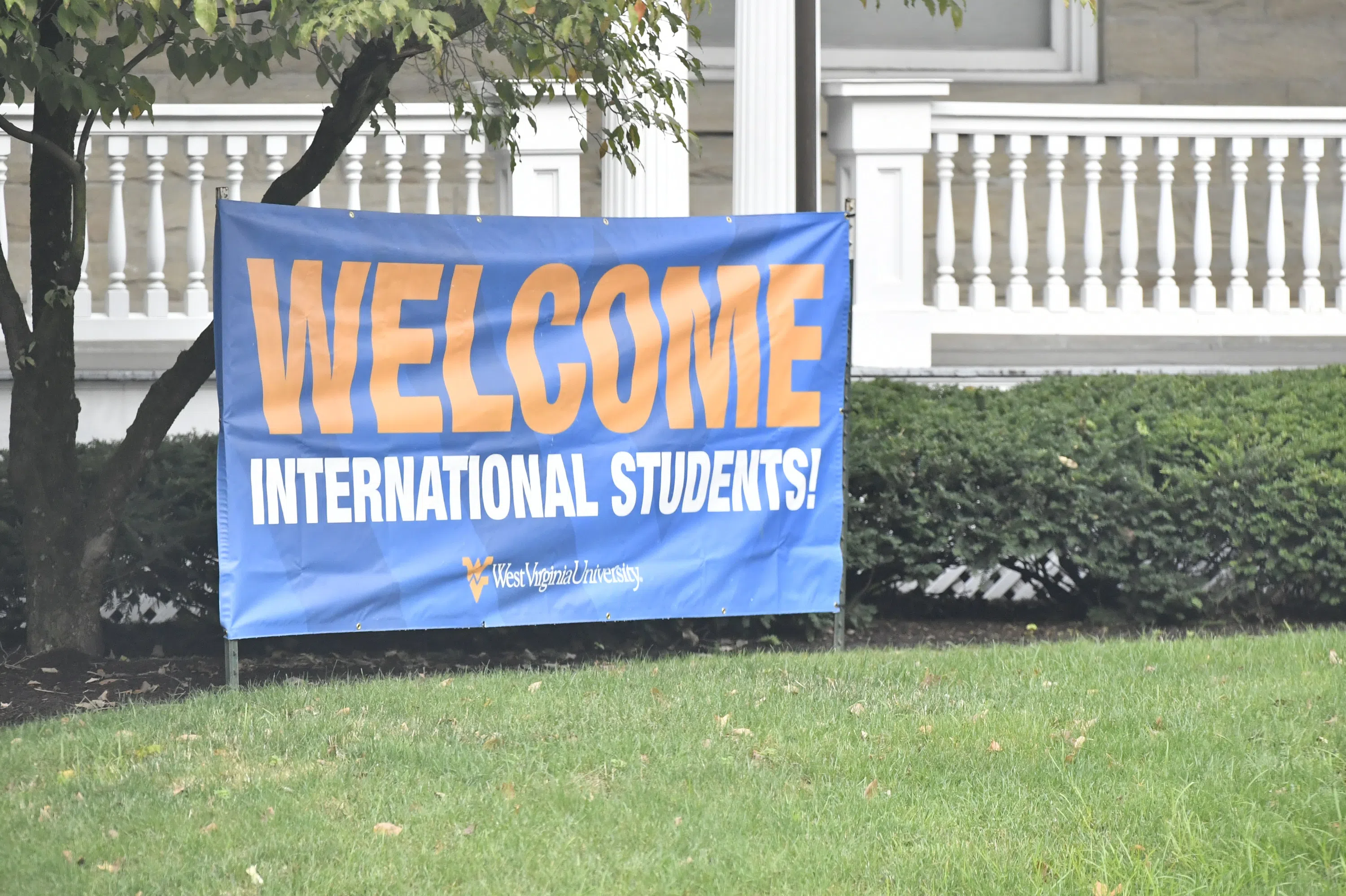 A banner that reads "Welcome International Students" is hung on the front balcony of the Purinton House. 