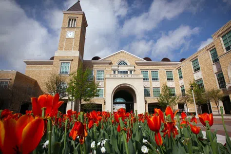 The student union against a blue sky with red tulips in the foreground