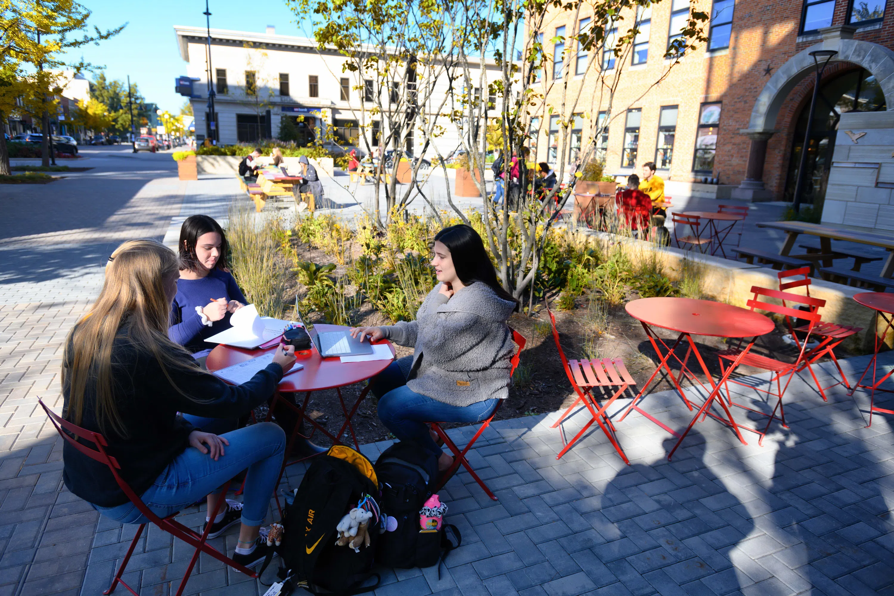Students sitting at a table in the Pedestrian Mall in downtown Iowa City