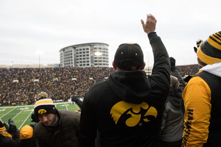 Man participating in "the wave" by waving to the children in the children's hospital located across from Kinnick Stadium