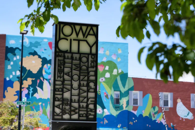 Iowa City sign set against background of murals in downtown Iowa City