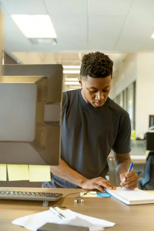 Student using computer and writing down notes