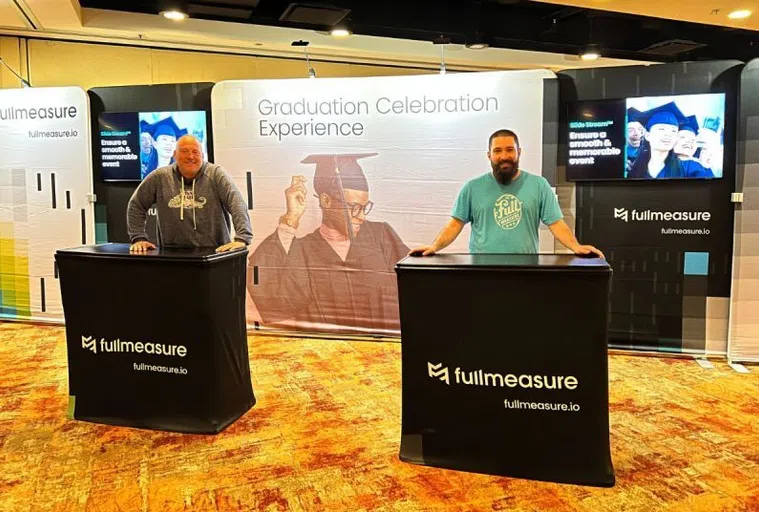 2 Full Measure employees attending the booth at a conference