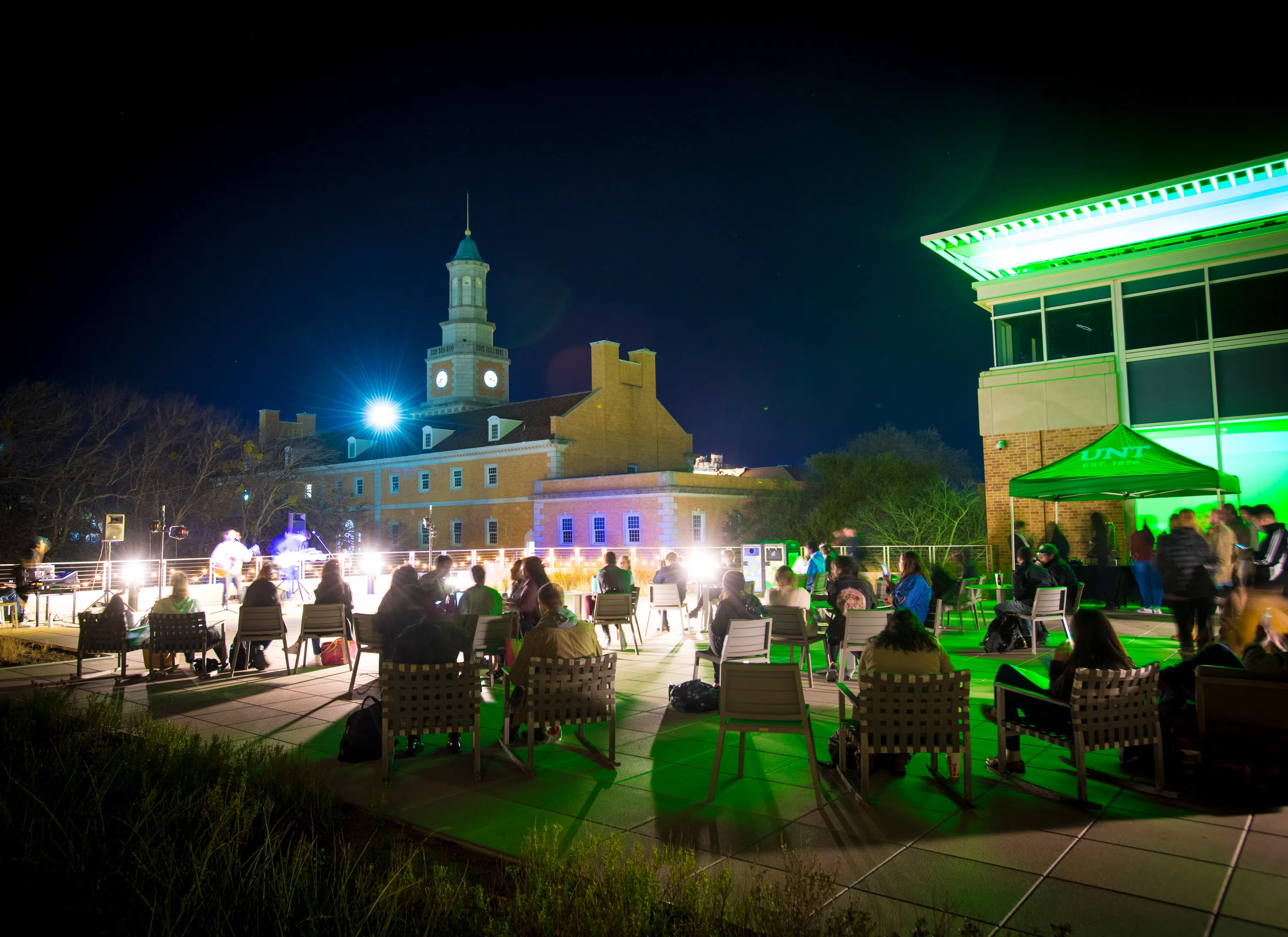 People gather on the rooftop of the Union to listen to a live musician at night. 