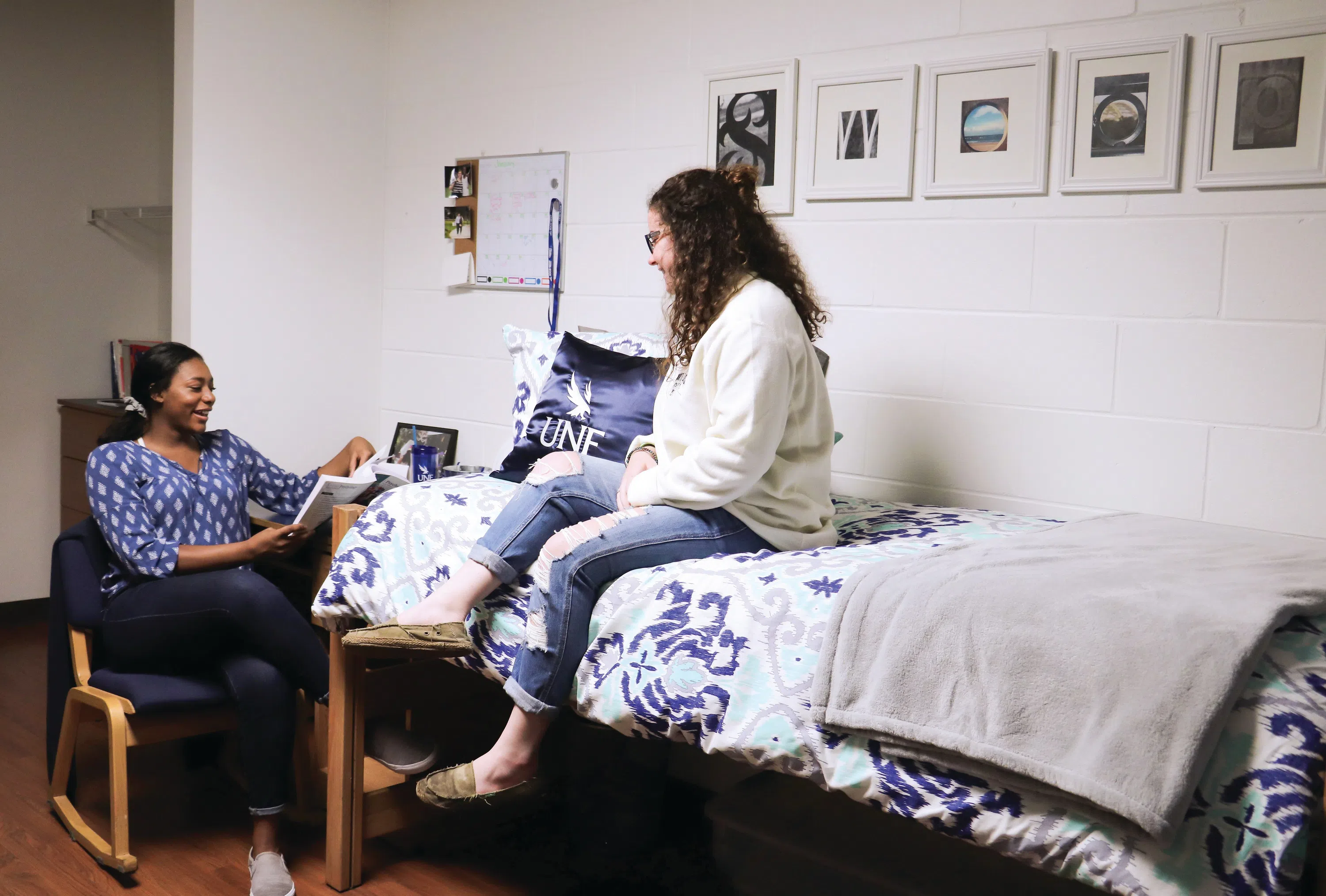 Two students talking while sitting on bed and desk chair