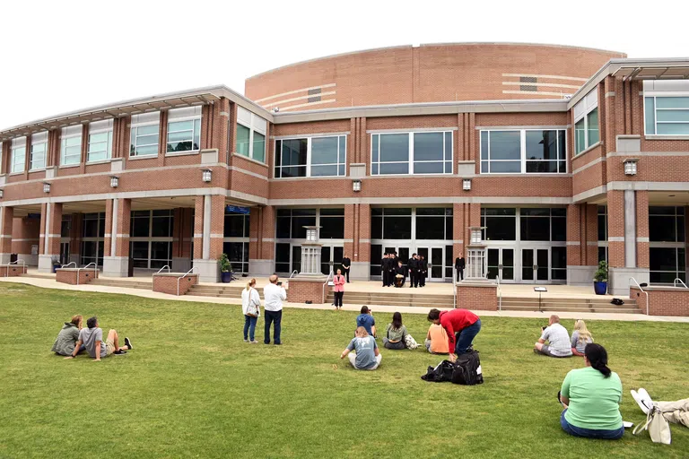 People gathered on the green watching a performance on the front steps of the Fine Arts Center