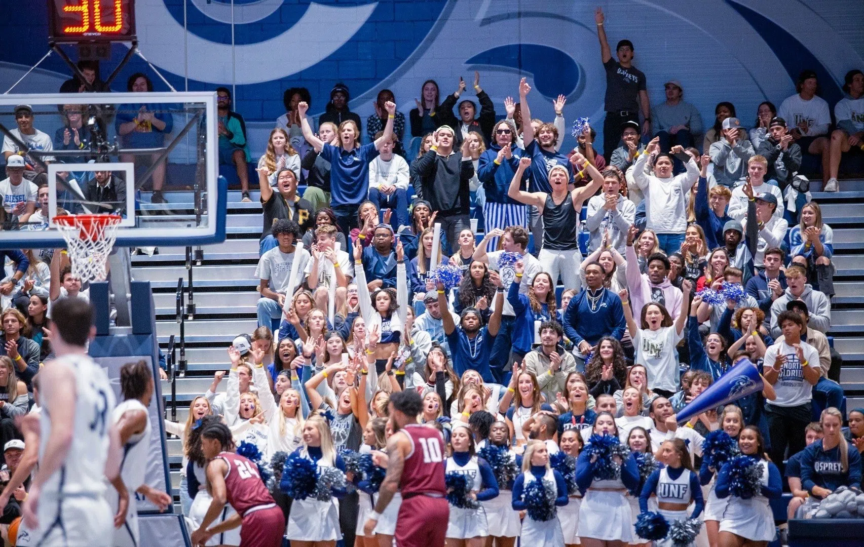 Students standing and cheering in the stands at basketball game