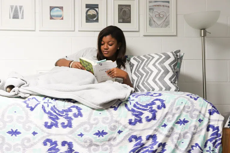 Student reading book in bed 