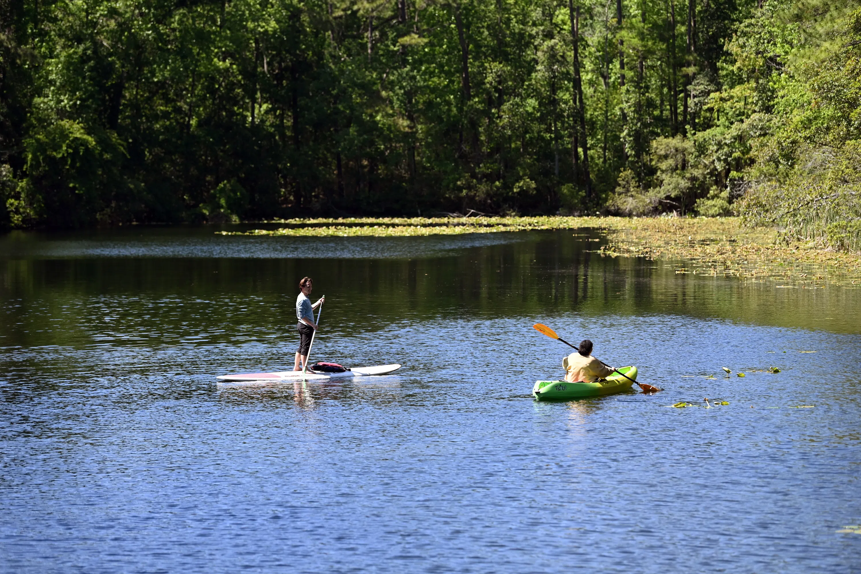 Two students out on the water on a paddleboard and kayak