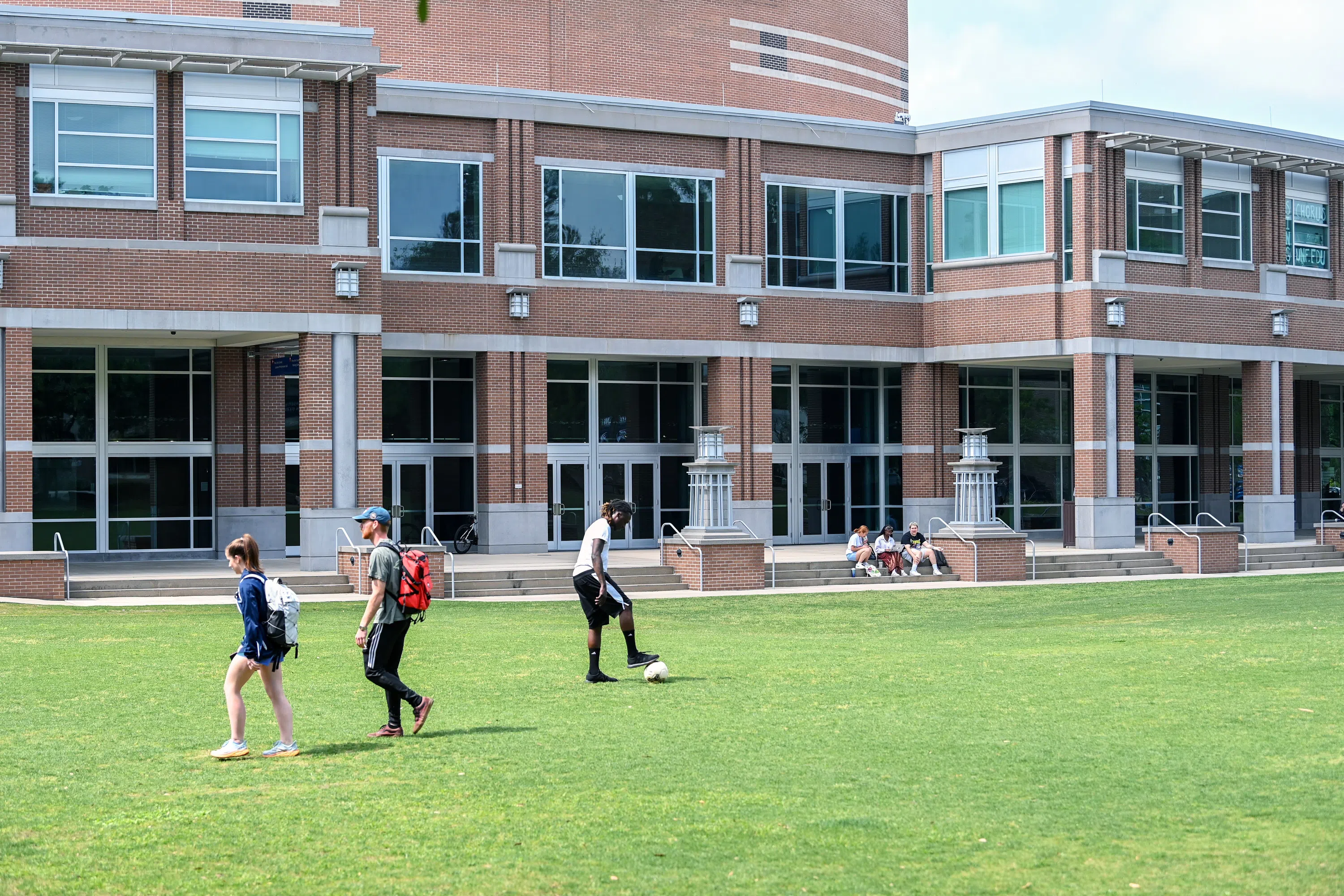 Students walking and playing soccer on the Green in front of the Fine Arts Center