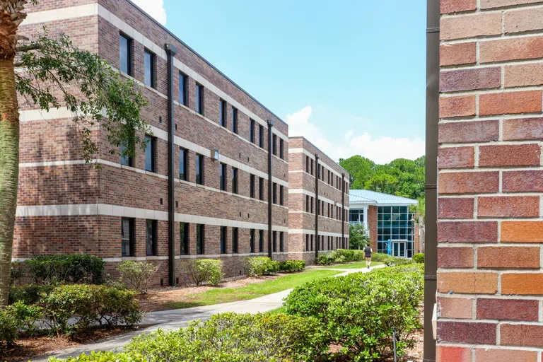 Student walking toward Osprey Clubhouse from between Osprey Cove Buildings