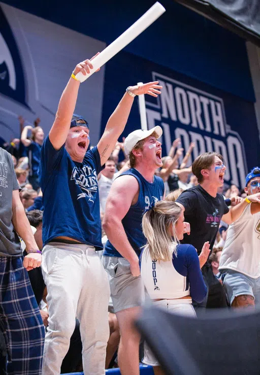 Students standing and cheering at a basketball game