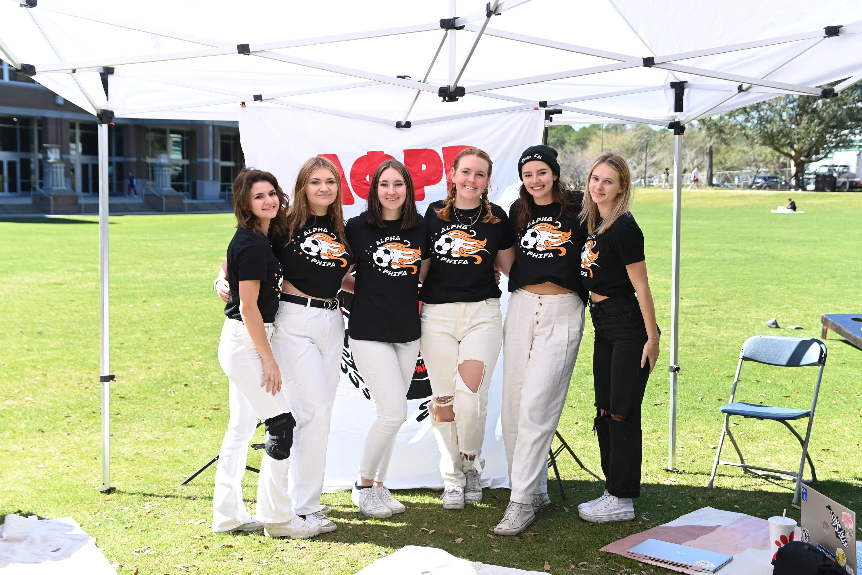 Group of sorority girls smiling for a picture at their tent on the green