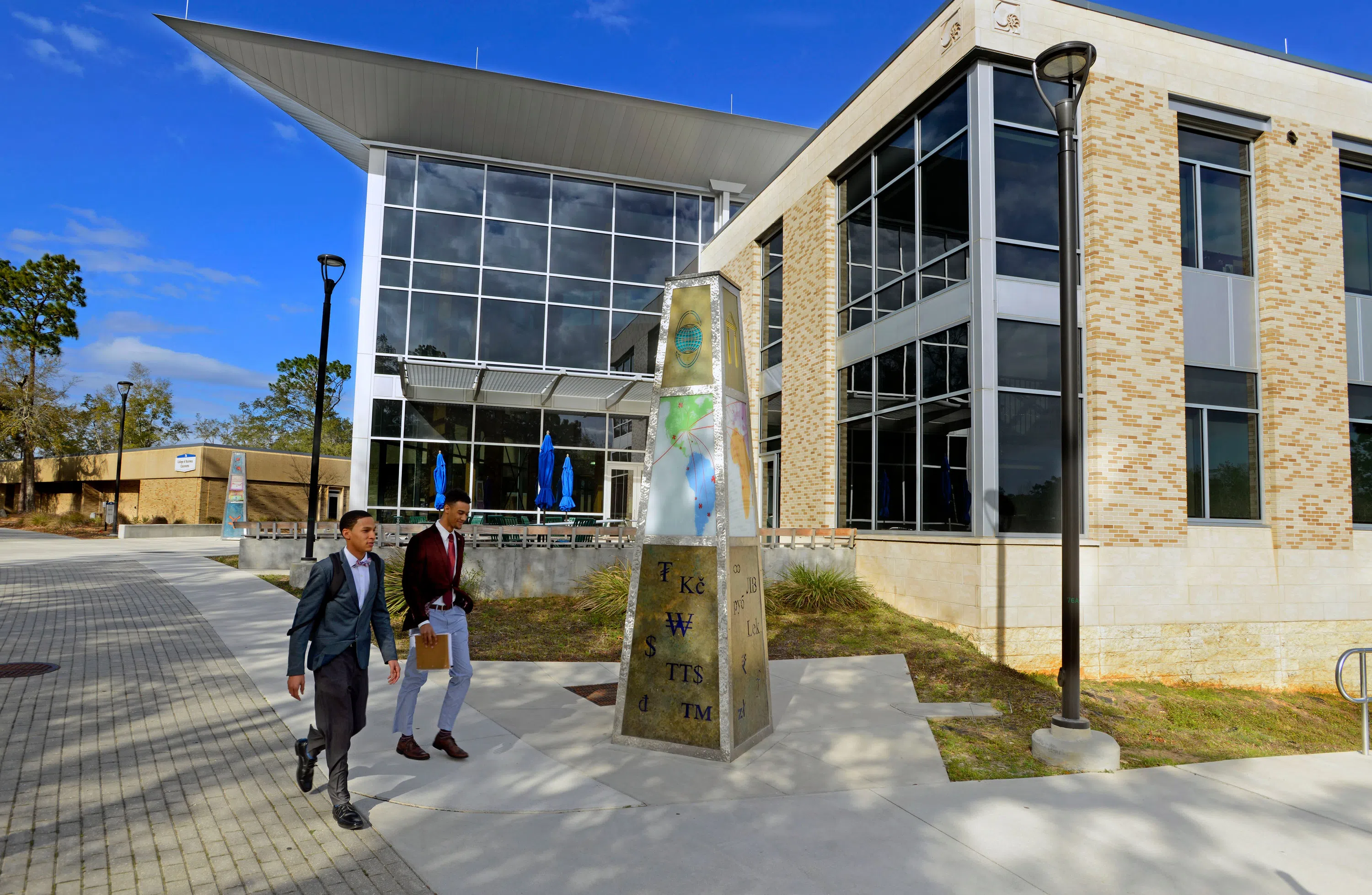 Two students in suits walking past the Lewis Bear Jr. College of Business.