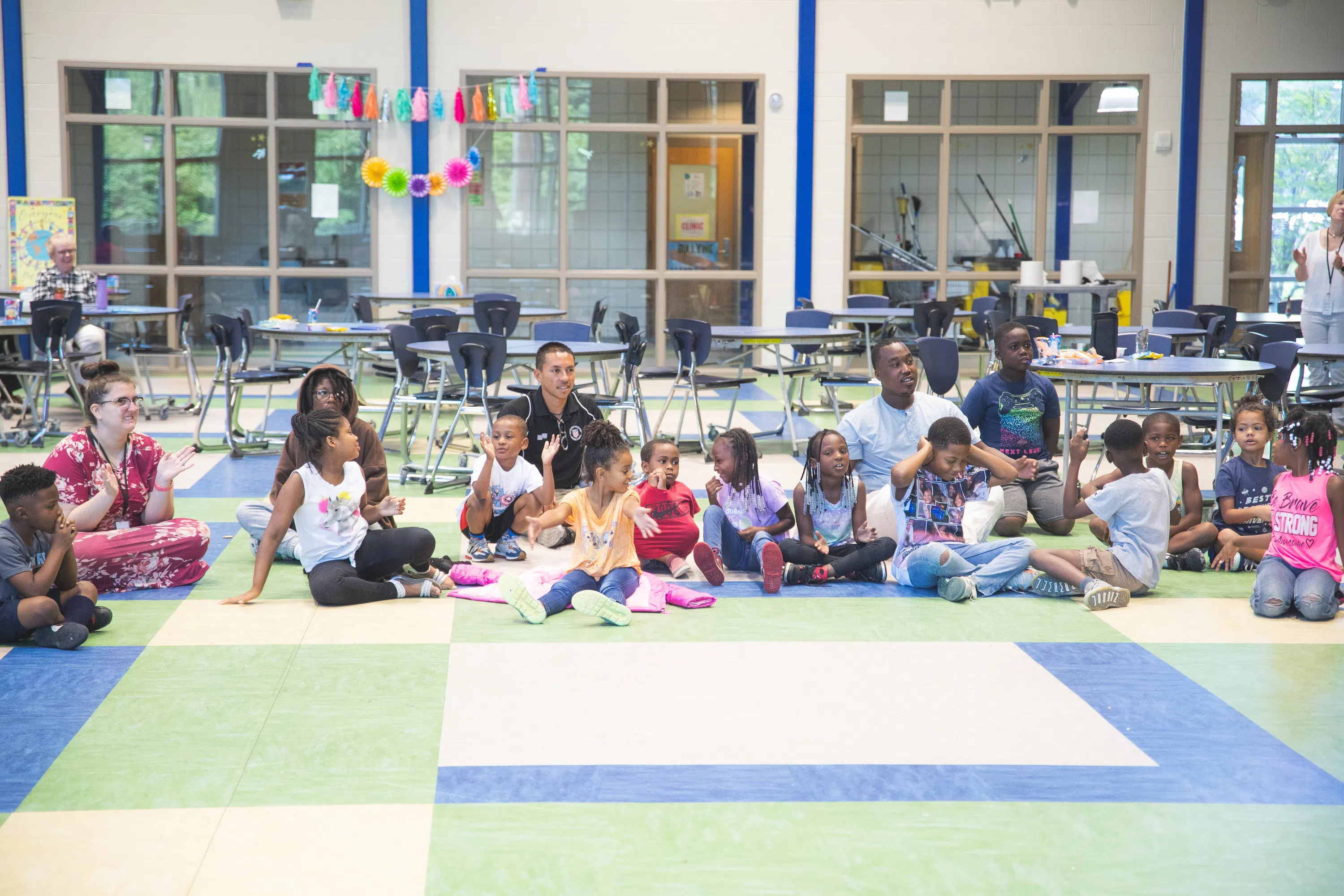 UWF students interacting with children in a cafeteria at an elementary school.