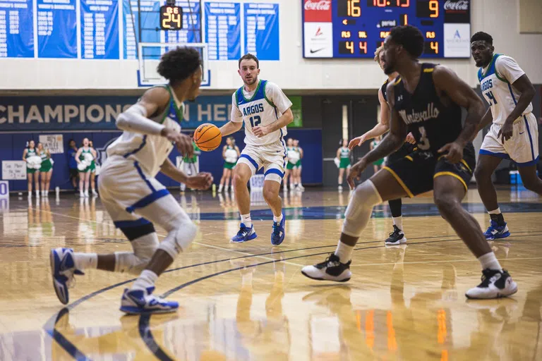 Men's basketball player dribbling ball down the court.