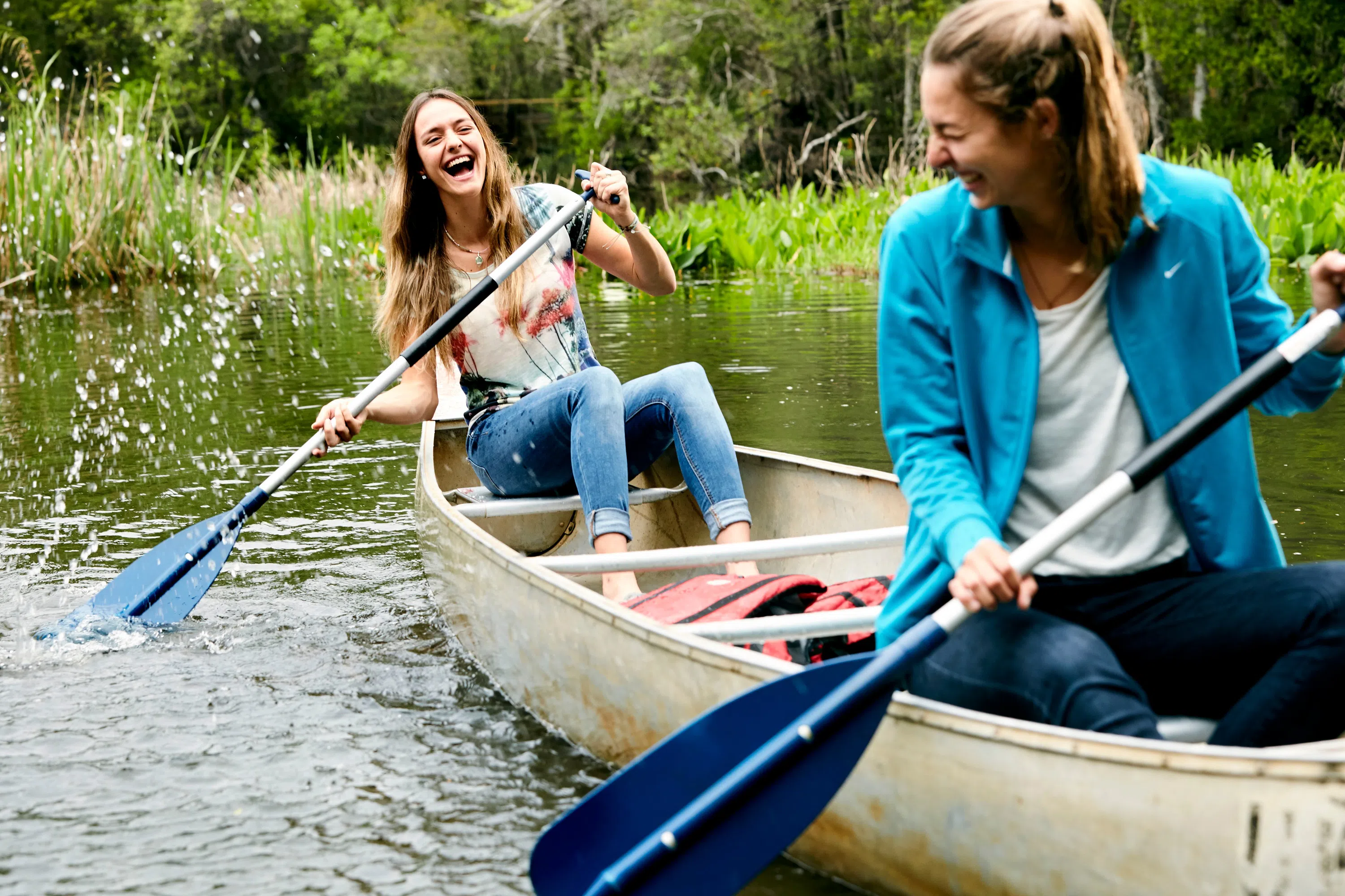 Two students paddling a canoe on the bayou. 