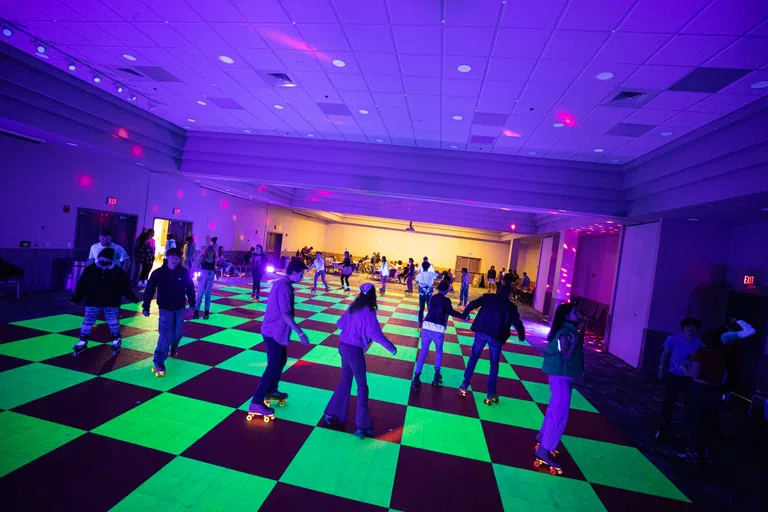 Students roller skating in a black light neon roller rink in the Conference Center