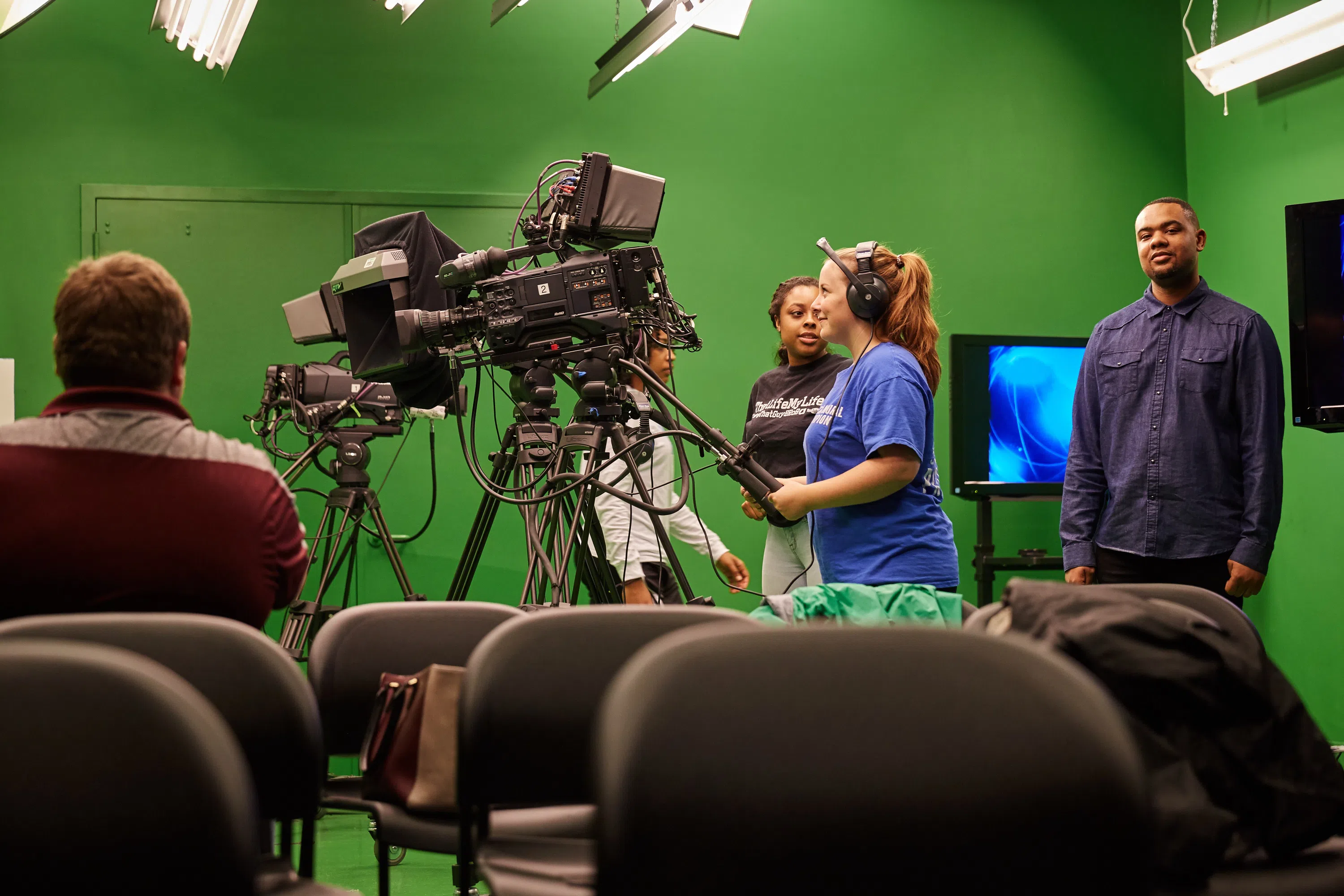 Students behind tv camera producing a show in the Communications TV Studio 