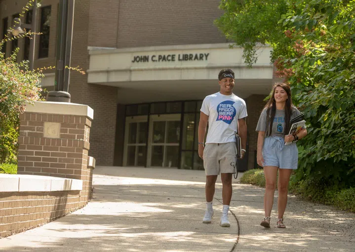 Male and female student walking out of the Pace Library entrance