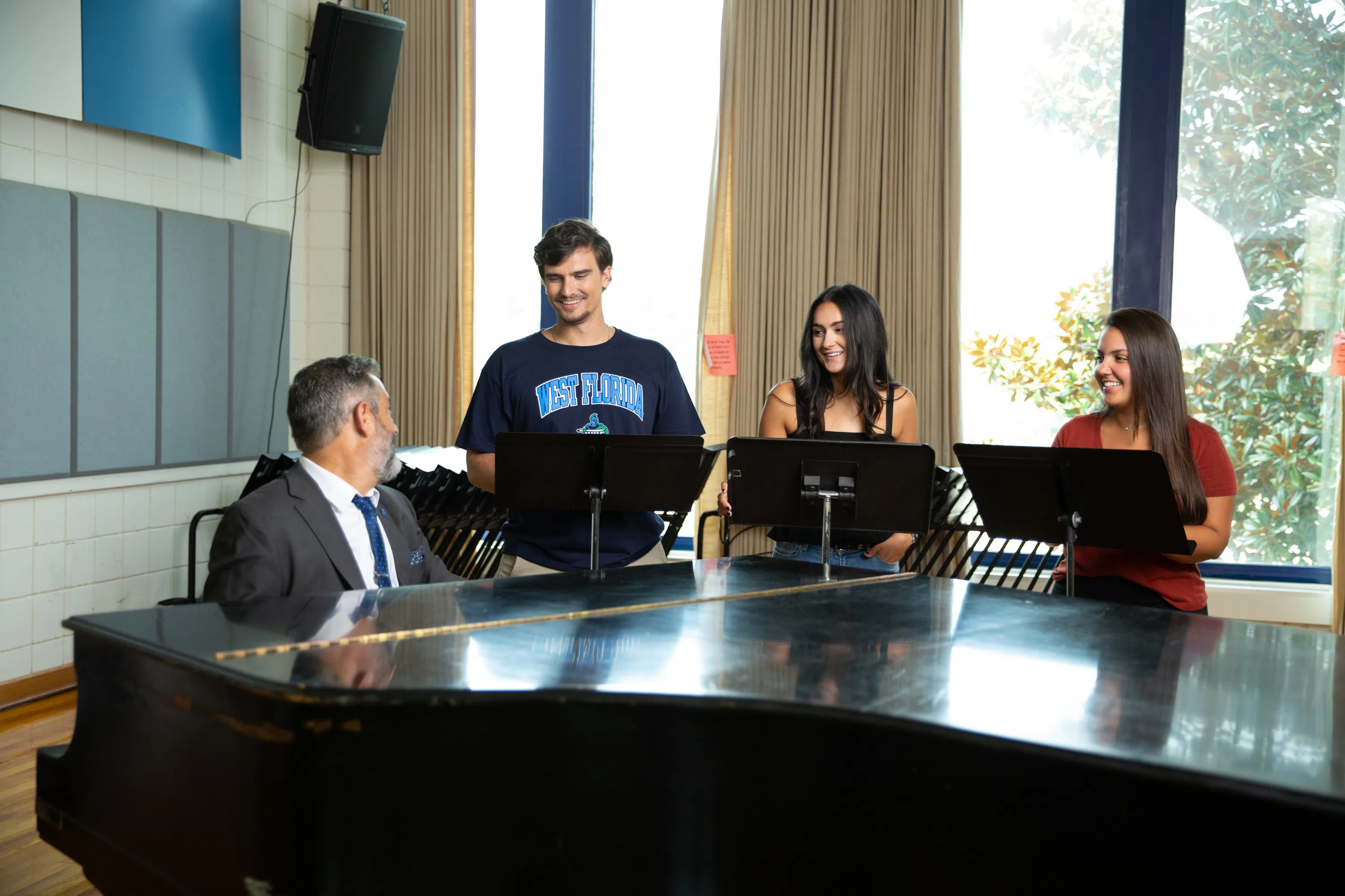 Students singing along side a grand piano