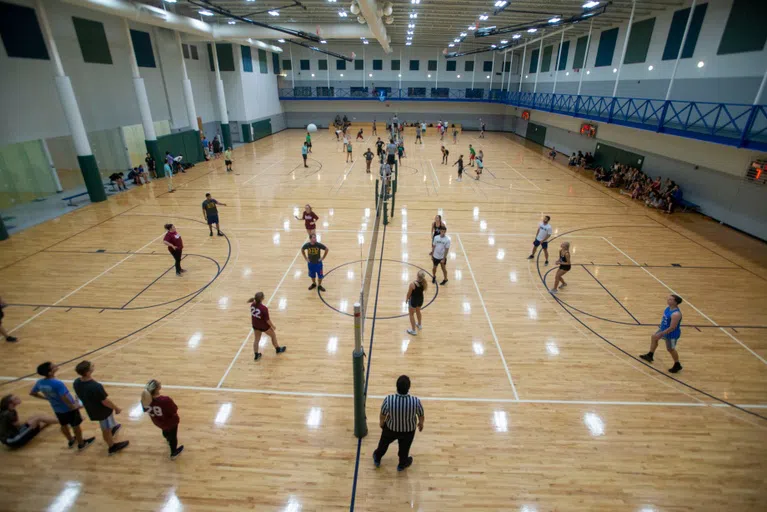 Students playing volleyball on the courts in the HLS.