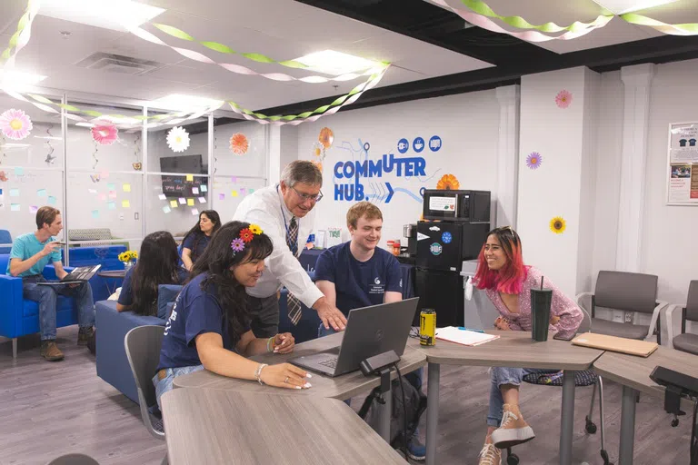 A staff person helps students log in to the network in the commuter hub