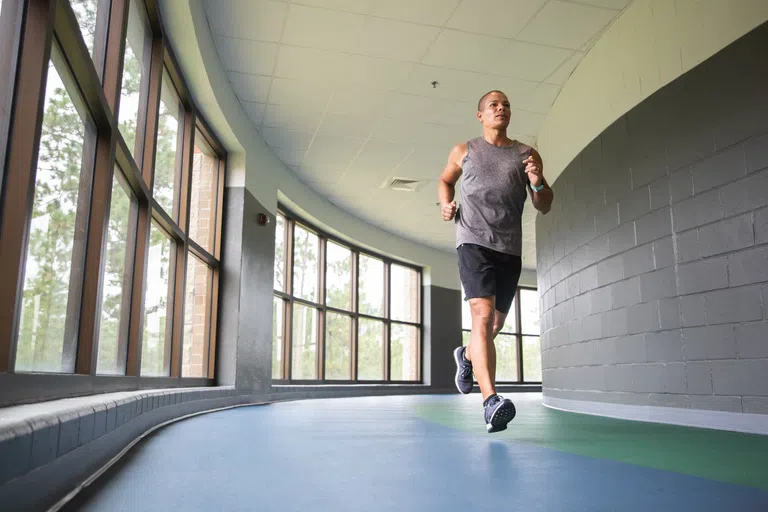 Student running on indoor track. 