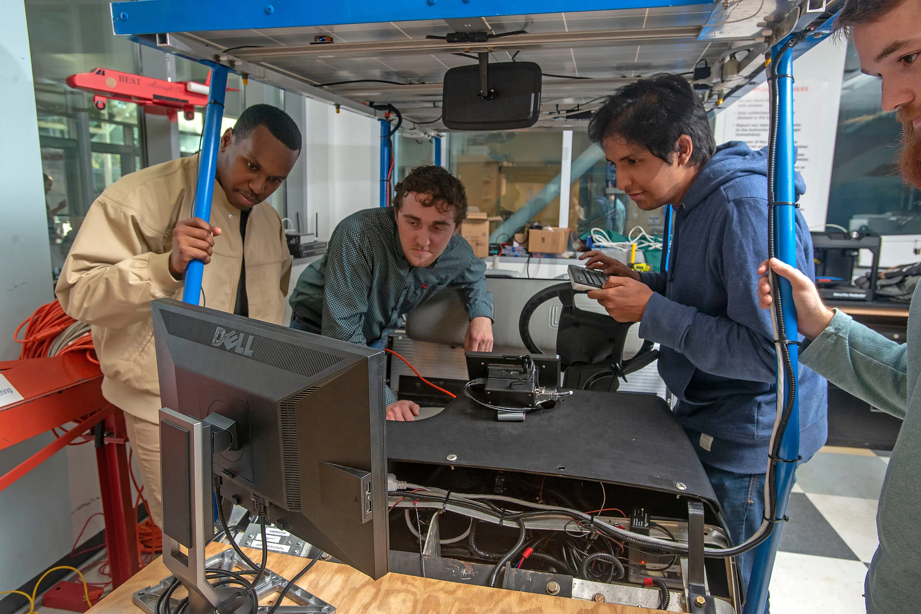 Three students working on a golf cart robotics project
