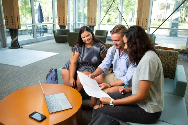 Three students meeting in the Lewis Bear Jr. College of Business Atrium. 