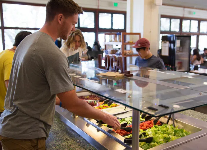 student serves themself at a salad bar