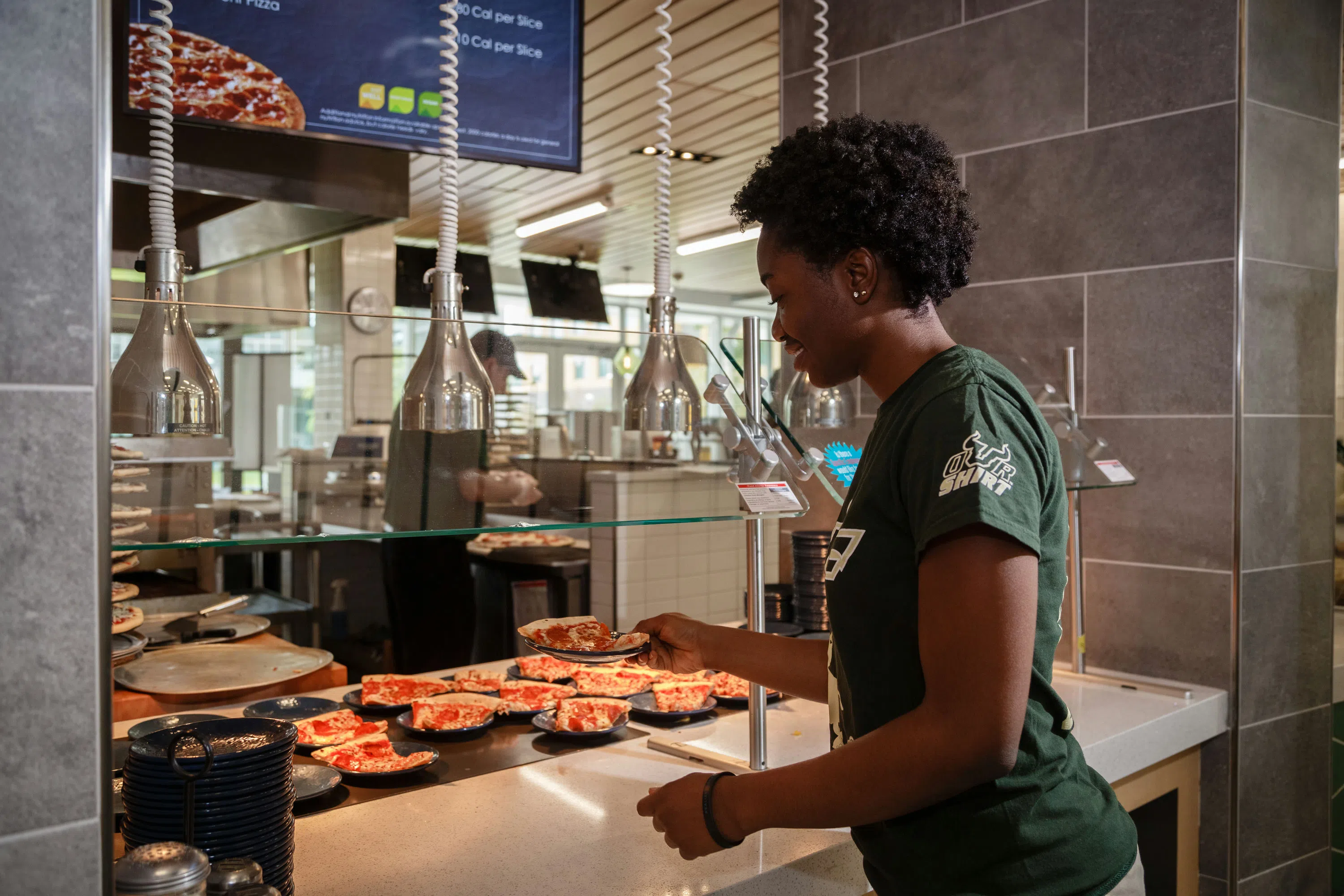 A student grabbing a slice of pizza at The Hub dining hall.