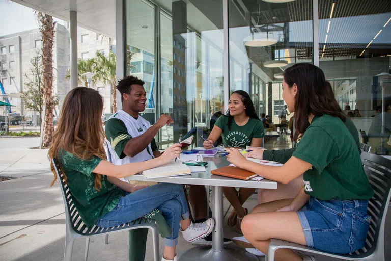 Students sitting at a table outside of The Hub dining hall/