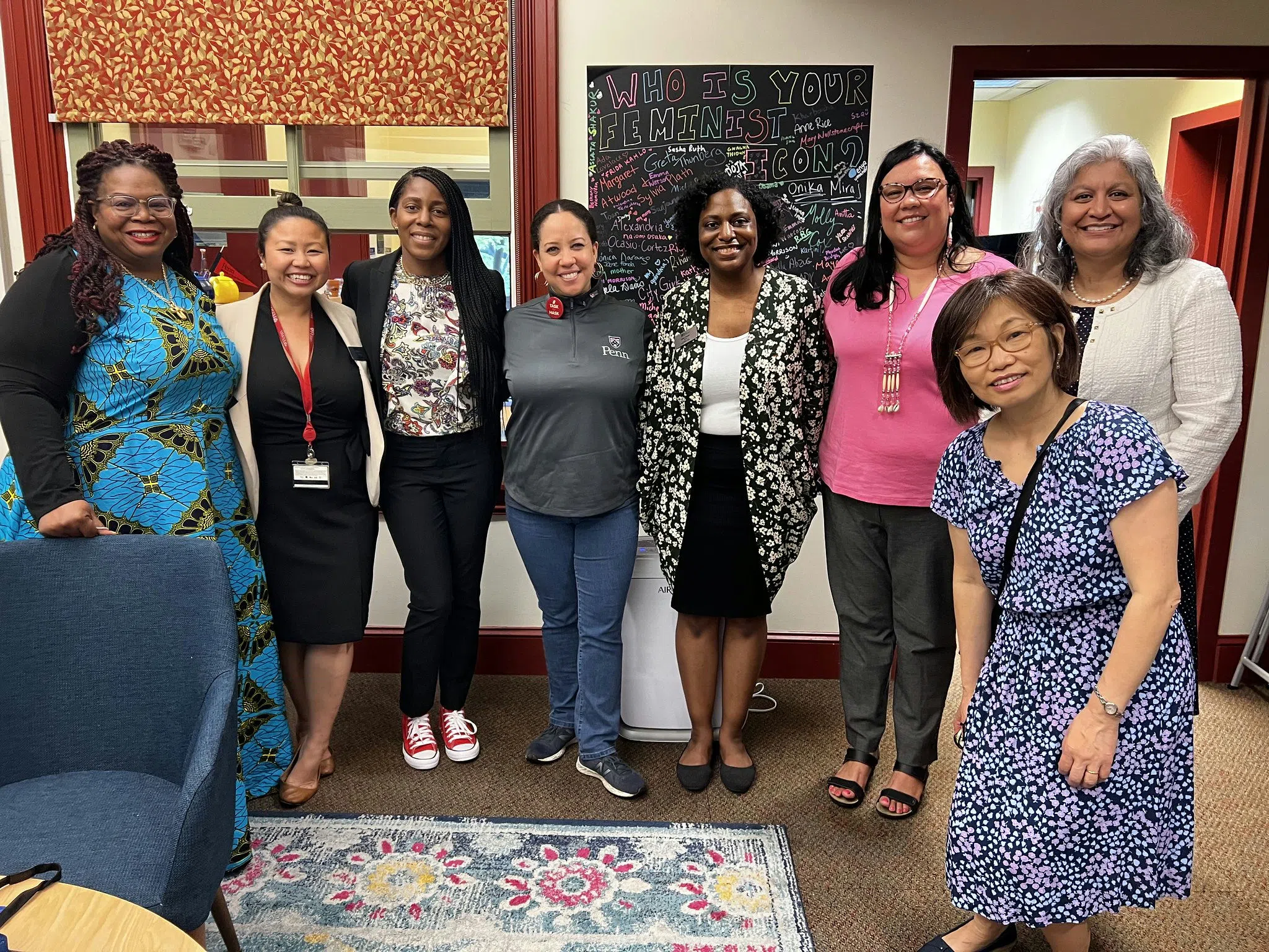 Women's Center staff and staff from other Cultural Resource Centers gather in a cozy, well-decorated space with a chalkboard that asks, "Who is your feminist icon?" and various responses.