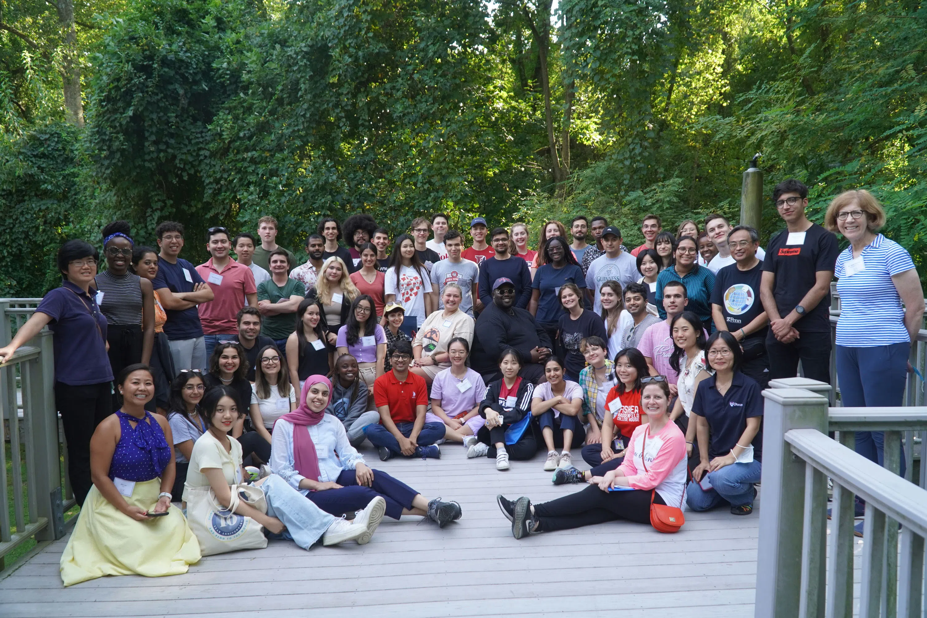 Sixty GIC staff and students stand on a patio, smiling, surrounded by natural beauty, attending a retreat.