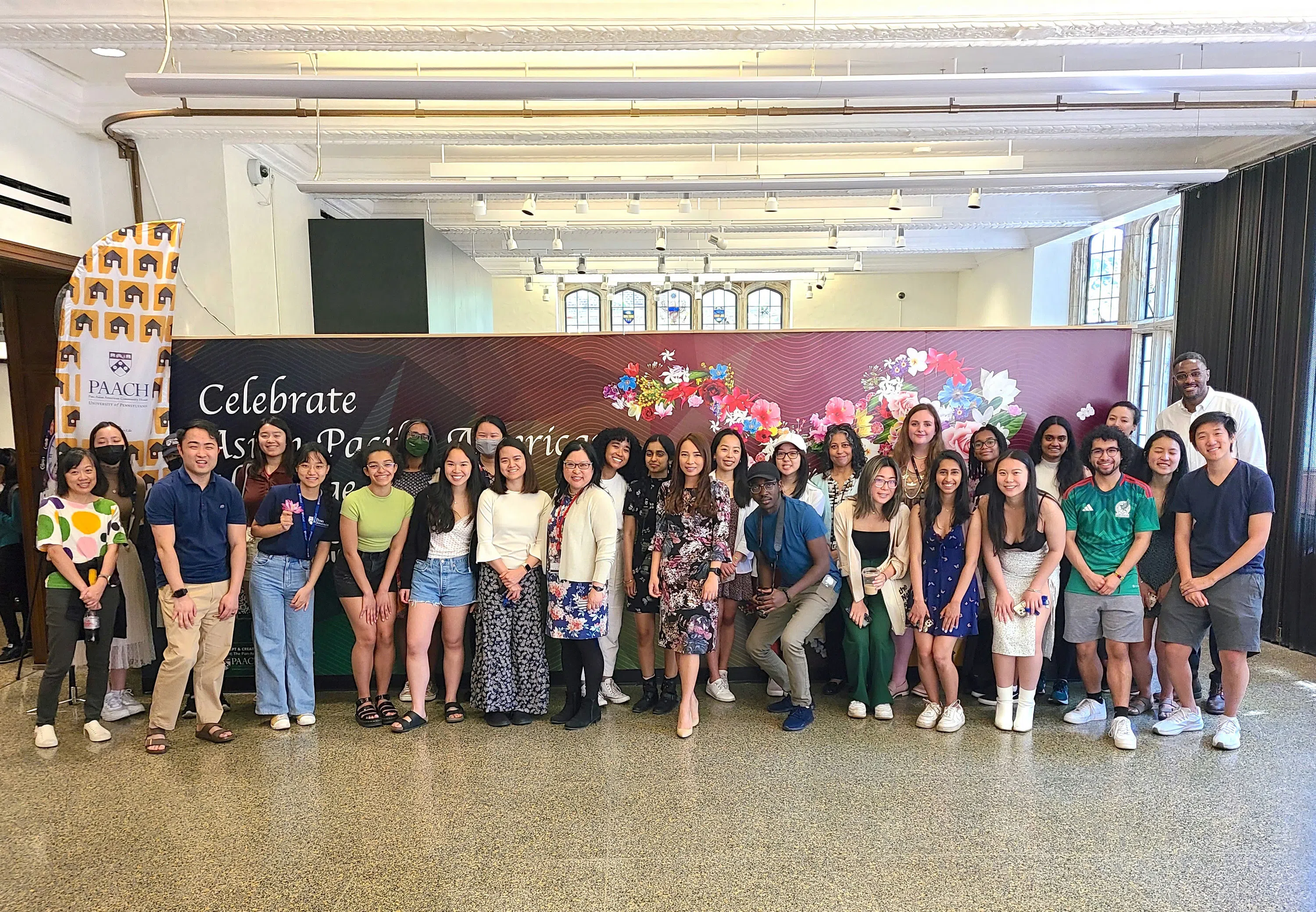 Thirty students, staff, and supporters of PAACH stand together in front of an indoor mural. Partially obscured behind the group, there is text that reads "Celebrate Asian Pacific American Heritage Month".