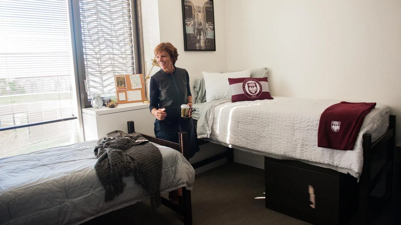 A woman stands inside a dorm room 