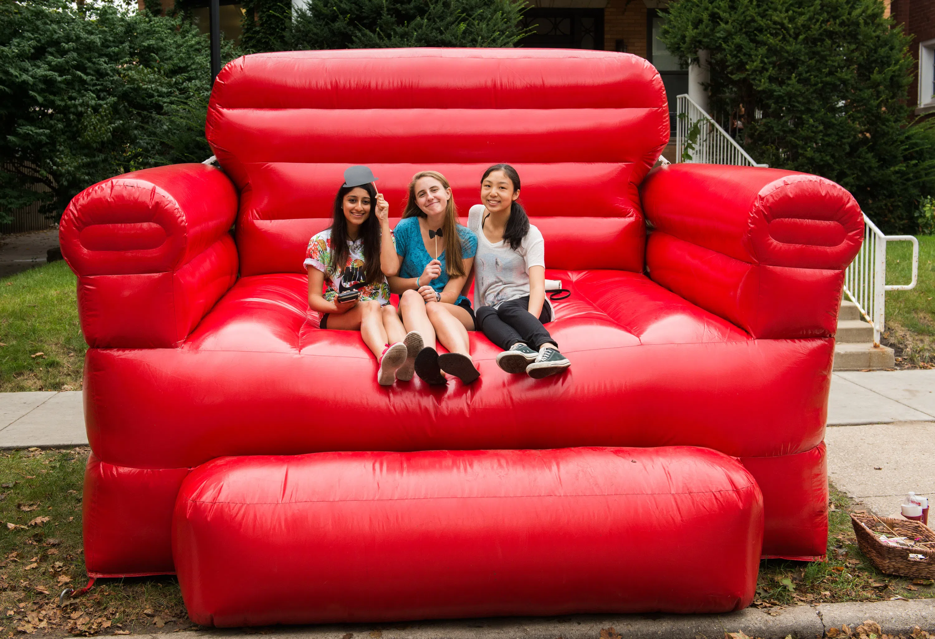 3 students sitting on a giant red inflatable sofa