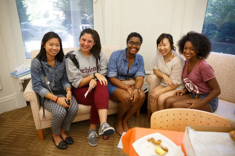 5 students sit alongside each other, smiling