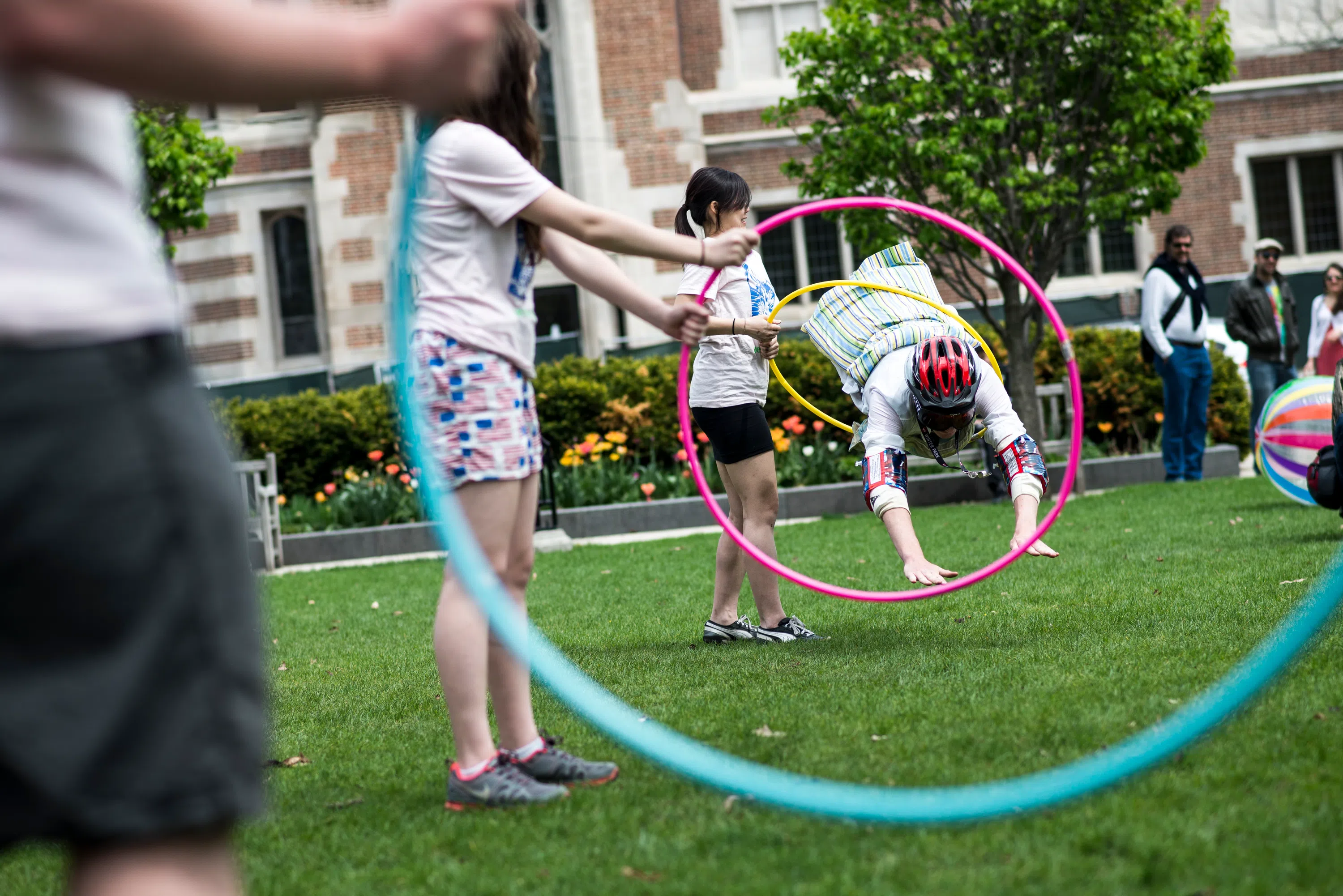 Student dives through a hula hoop onto the grass on the quad