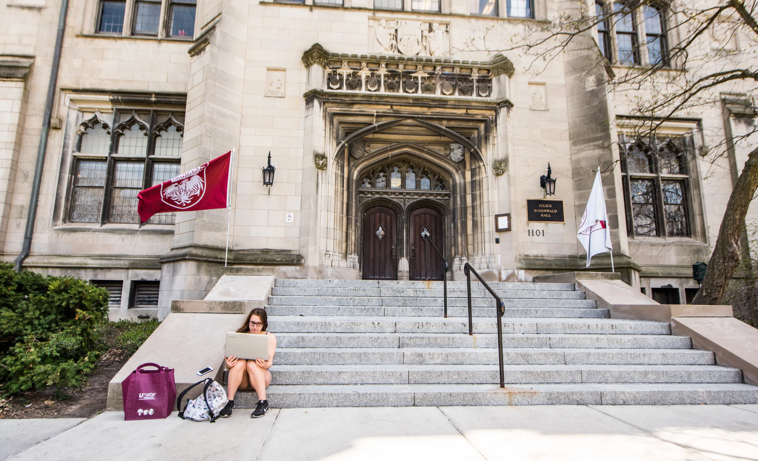 student sits at the foot of the steps to entrance to admissions office