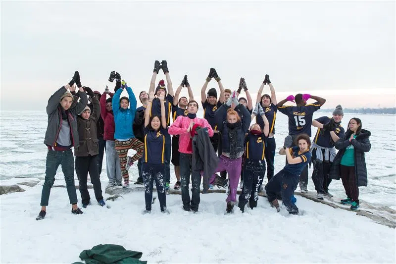 students pose in a large group on the snowy lakefront on an overcast day
