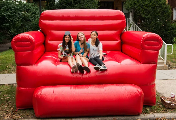 3 students sitting on a giant red inflatable sofa