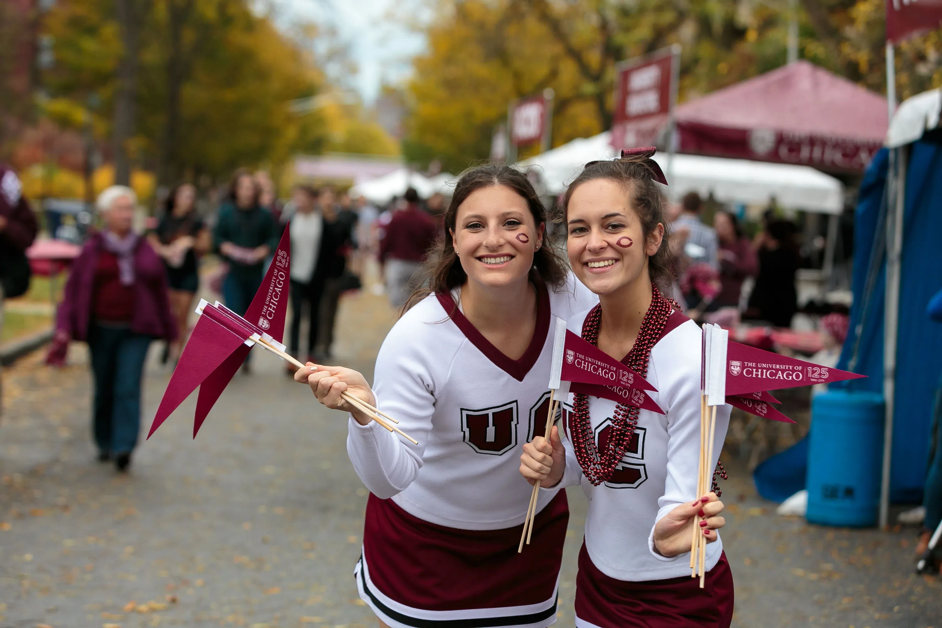 two UChicago cheerleaders hold up small flags during Homecoming