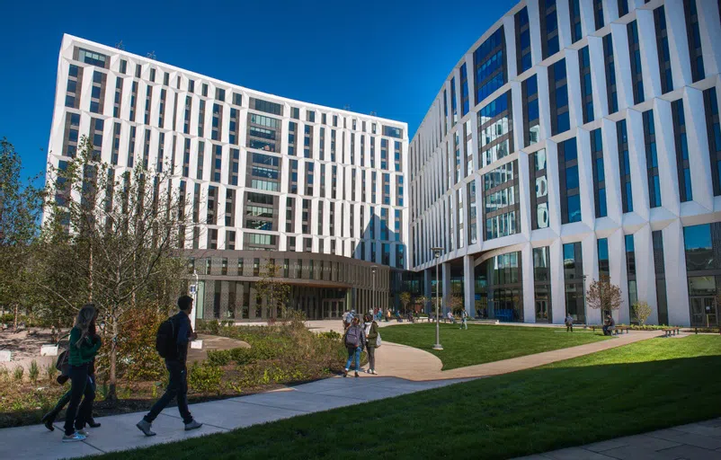 Exterior of the residential commons, a cluster of 3 white modern buildings with large windows and a large courtyard in the middle