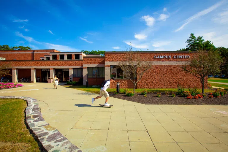 Long brick building against blue sky with student skateboarding in front