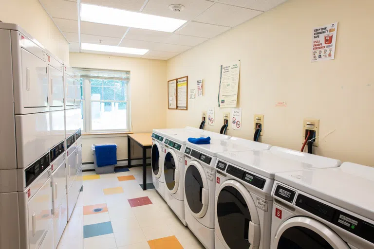 Row of stacked dryers on the left and a row of washers on the right. 