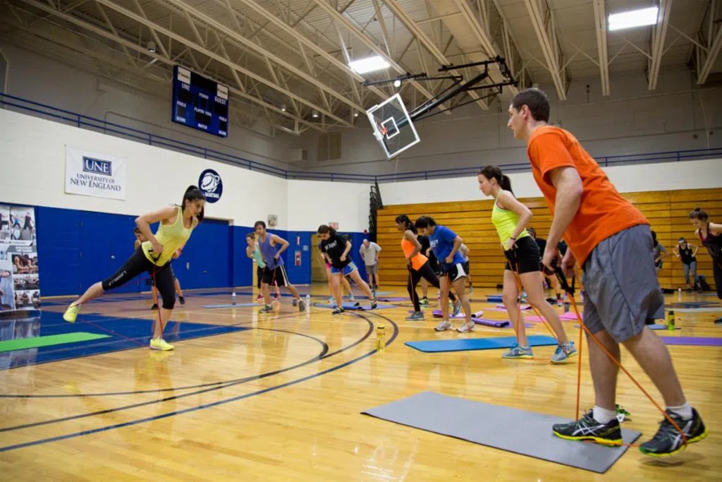 group of students do exercises on yoga mats with resistance bands