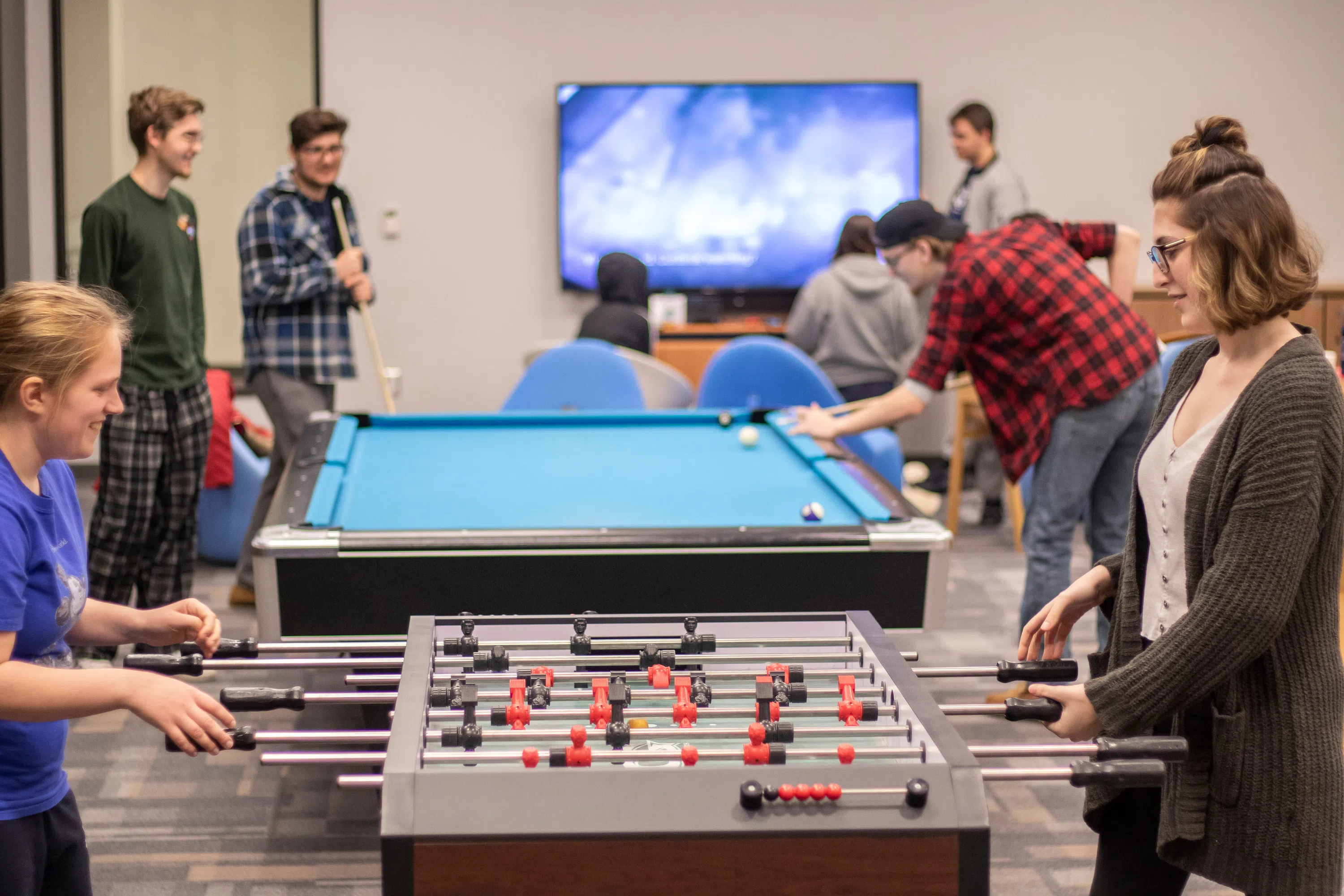 students play foosball, pool, and watch a television